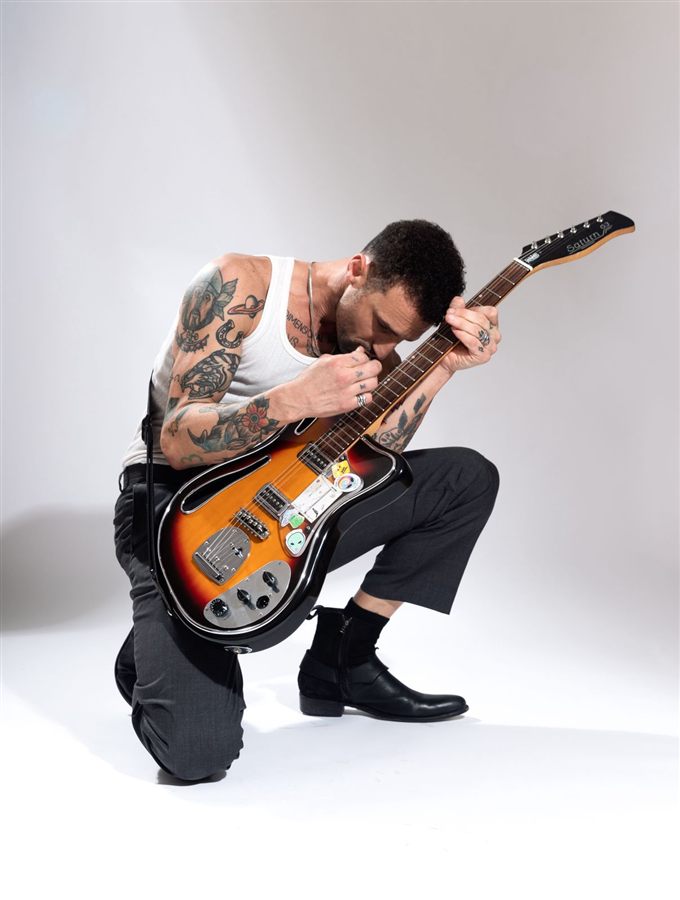 Pablo Malvin agachado, tocando la guitarra con intensidad