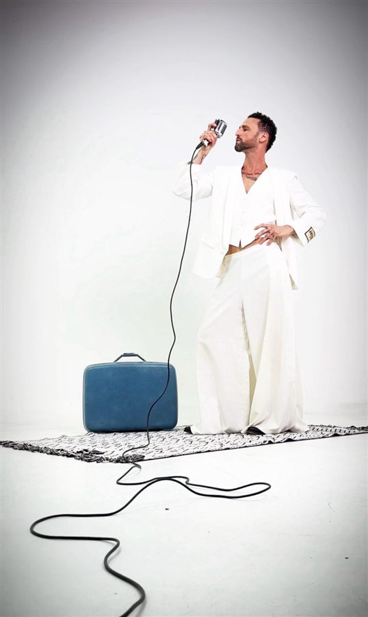 Pablo Malvin con traje blanco, cantando con micrófono vintage